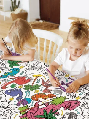 Children colouring a giant dinosaur-themed table cloth activity sheet from Tiny Explorers Hub